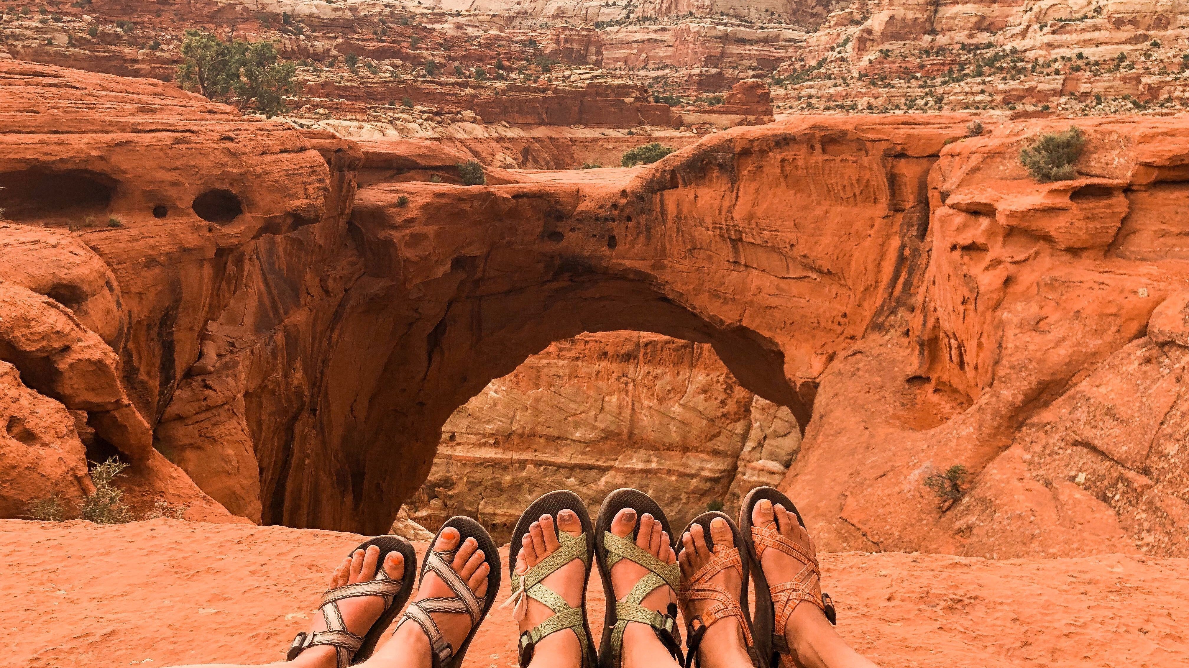 Three pairs of womens feet in sandals near the Capital Reef National Park.
