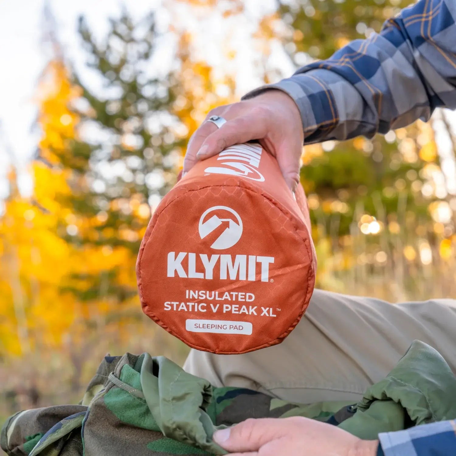Close-up of a red rock Klymit Insulated Static V Peak XL sleeping pad in its stuff sack.
