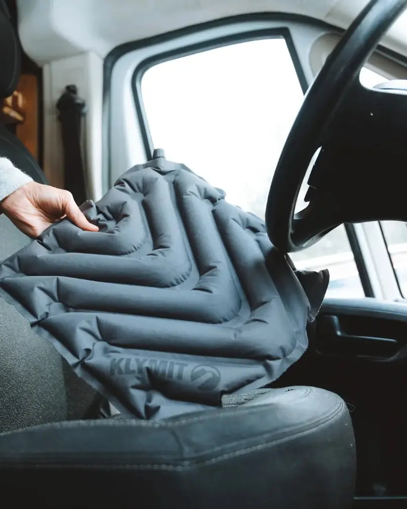 Person adjusting a Klymit V Seat pad inside a vehicle.
