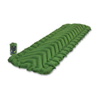 A rectangular green inflatable sleeping pad with v shaped pattern shown at an angle with its small stuff sack next to it.