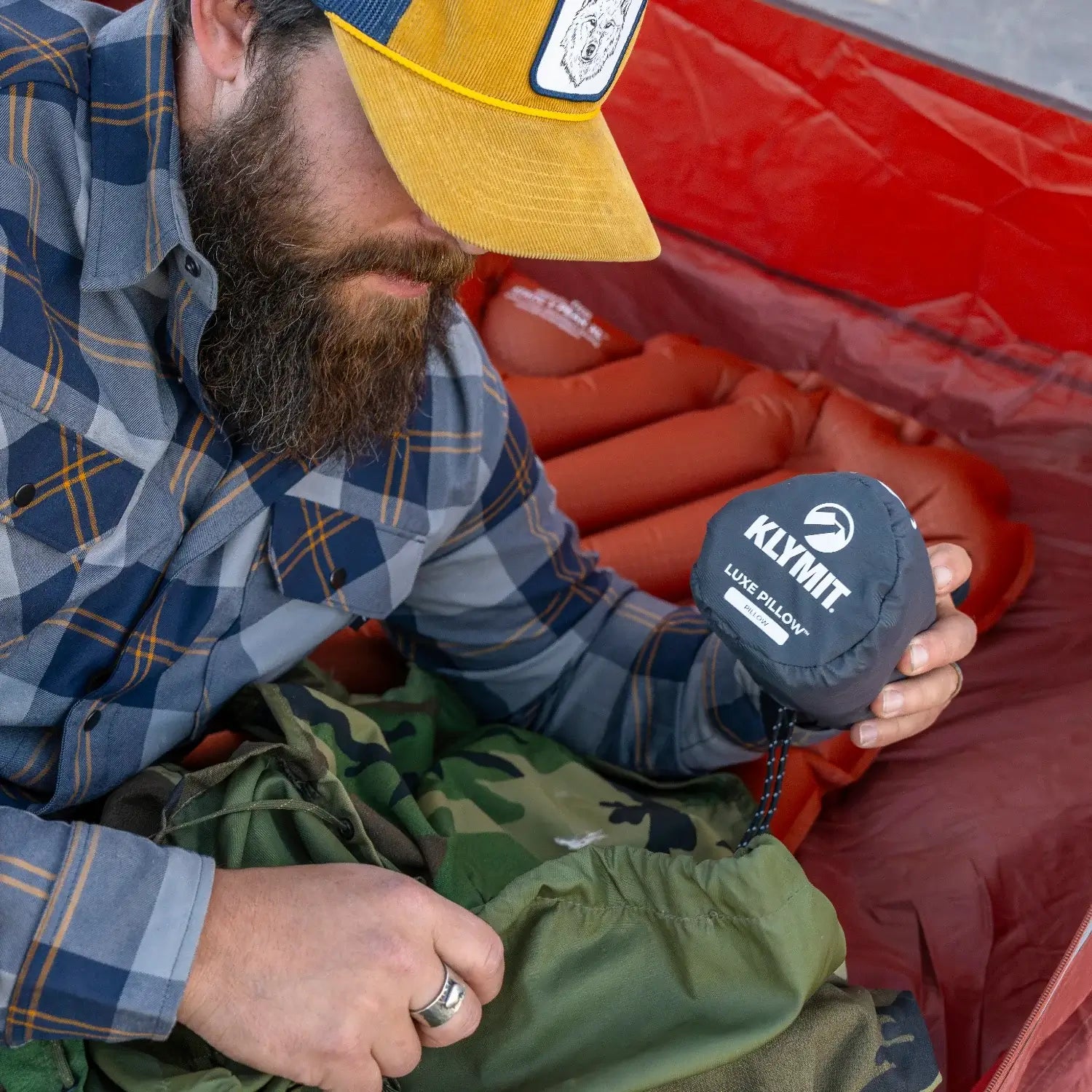 Man holding a Klymit Pillow X Luxe Summit in its stuff sack inside a tent.