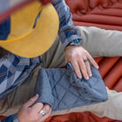 Overhead close-up of a man unfolding a Klymit Pillow X Luxe Summit on a sleeping pad.