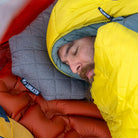 Close-up of a man sleeping on a Klymit Pillow X Luxe Summit inside a sleeping bag.