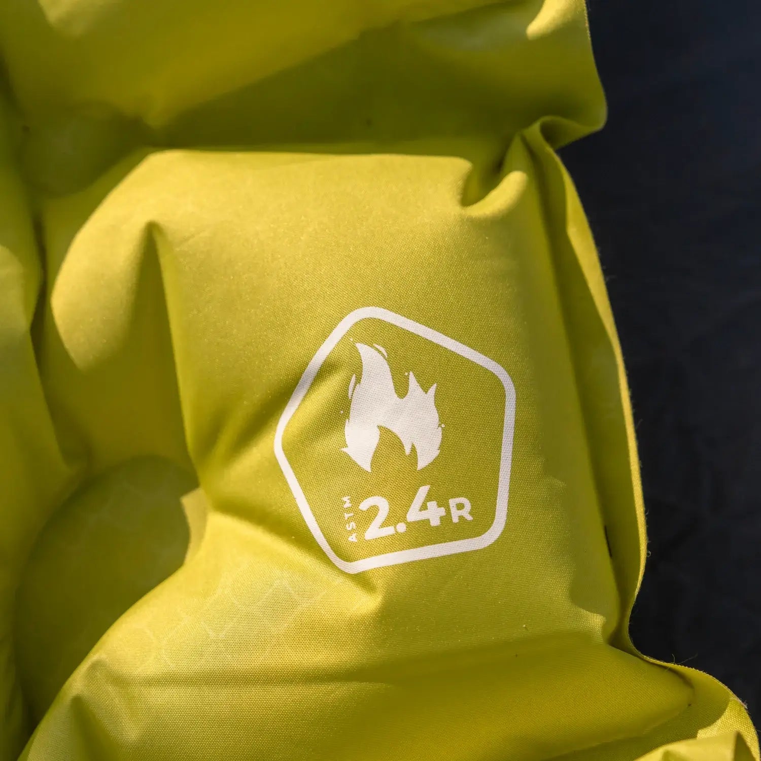 Close-up of a chartreuse Klymit Static V Summit sleeping pad showing its quilted air chambers and ASTM 2.4 R-value certification badge.