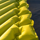 Detail shot of the chartreuse Klymit Static V Summit sleeping pad's V-shaped air chamber construction in warm sunlight.