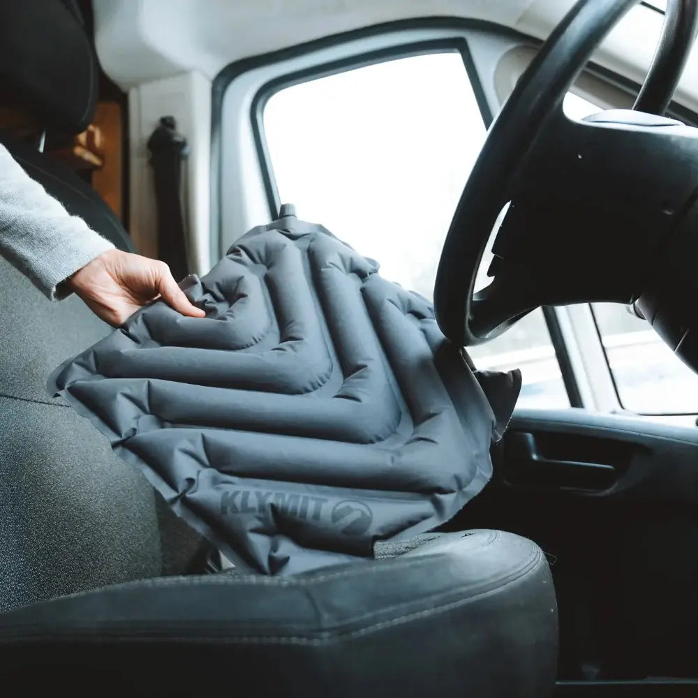 Person adjusting a Klymit V Seat pad inside a vehicle.