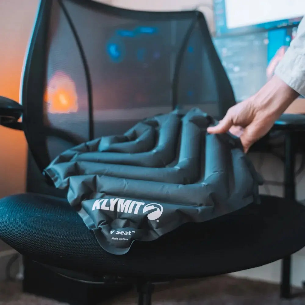 Inflatable V Seat cushion with KLYMIT branding being used on a chair.