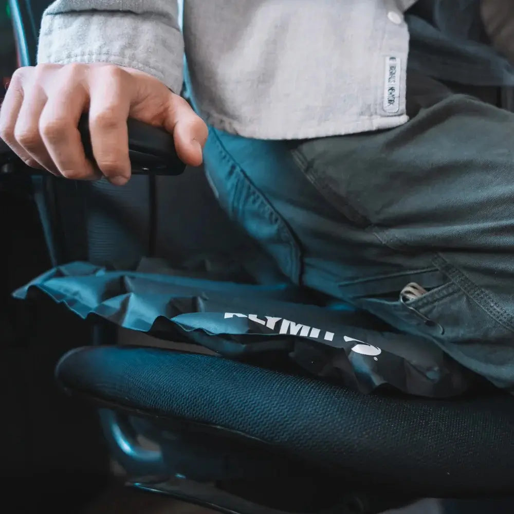 Person sitting in an office chair with a gray V Seat pad 