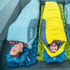 Overhead view of two people in a tent — woman in a Klymit Wild Aspen 20 Regular and man in a Klymit Wild Aspen 0 Degree Large sleeping bag, each on a Klymit sleeping pad.