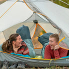 all-groups Two people laughing inside a tent with Klymit Wild Aspen 20 sleeping bags at a fall campsite.