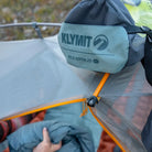 Close-up of the Klymit Wild Aspen 20 Regular stuff sack resting on a tent, with the sleeping bag being loaded inside.
