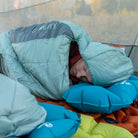 Man sleeping in a Klymit Wild Aspen 20 Large sleeping bag on a Klymit sleeping pad and pillow inside a tent.