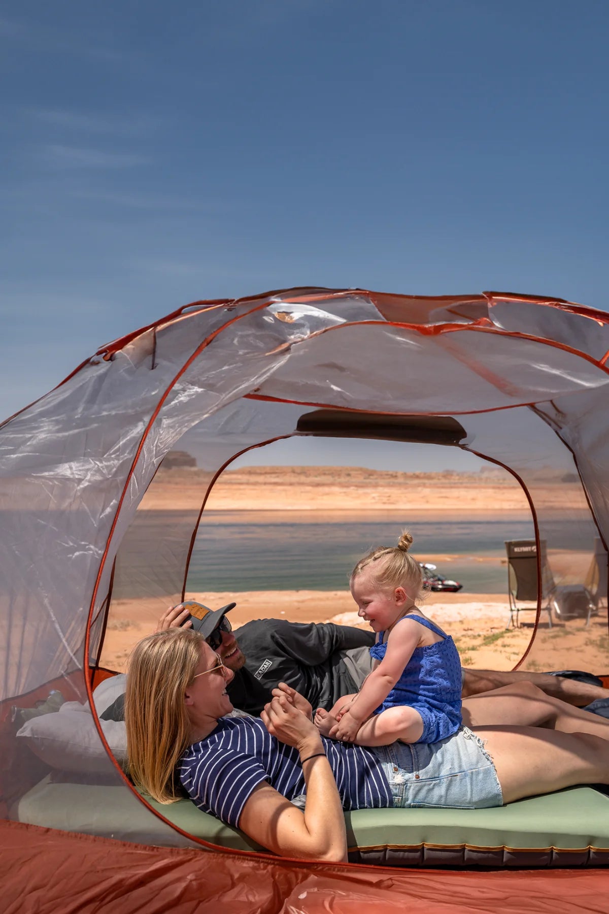 Family camping with Klymit Cross Canyon tent, Klymaloft Summit pad, and Drift Summit pillow at a lakeside desert campsite.