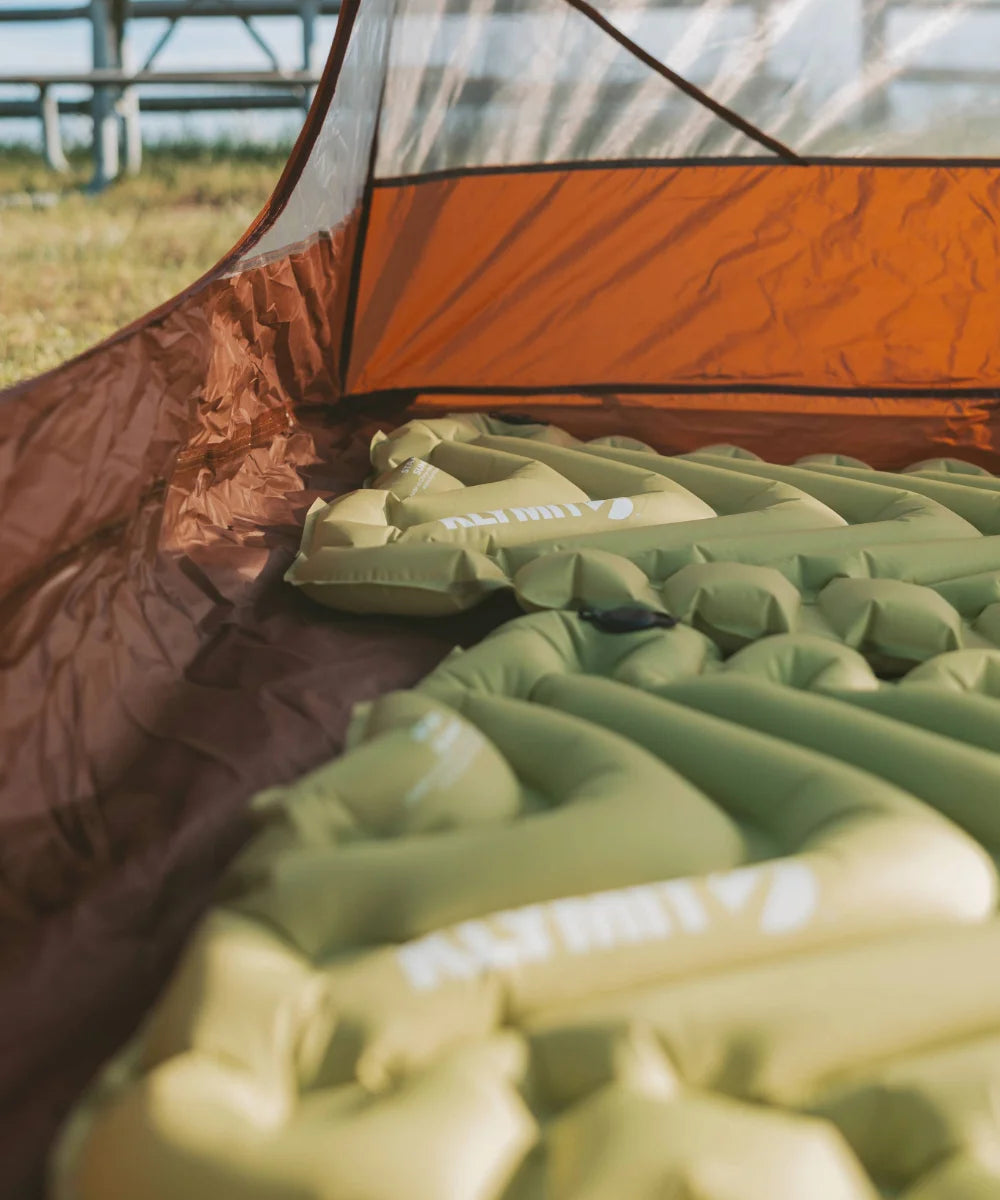 Close-up of chartreuse Static V Summit sleeping pads laid out inside an orange tent.